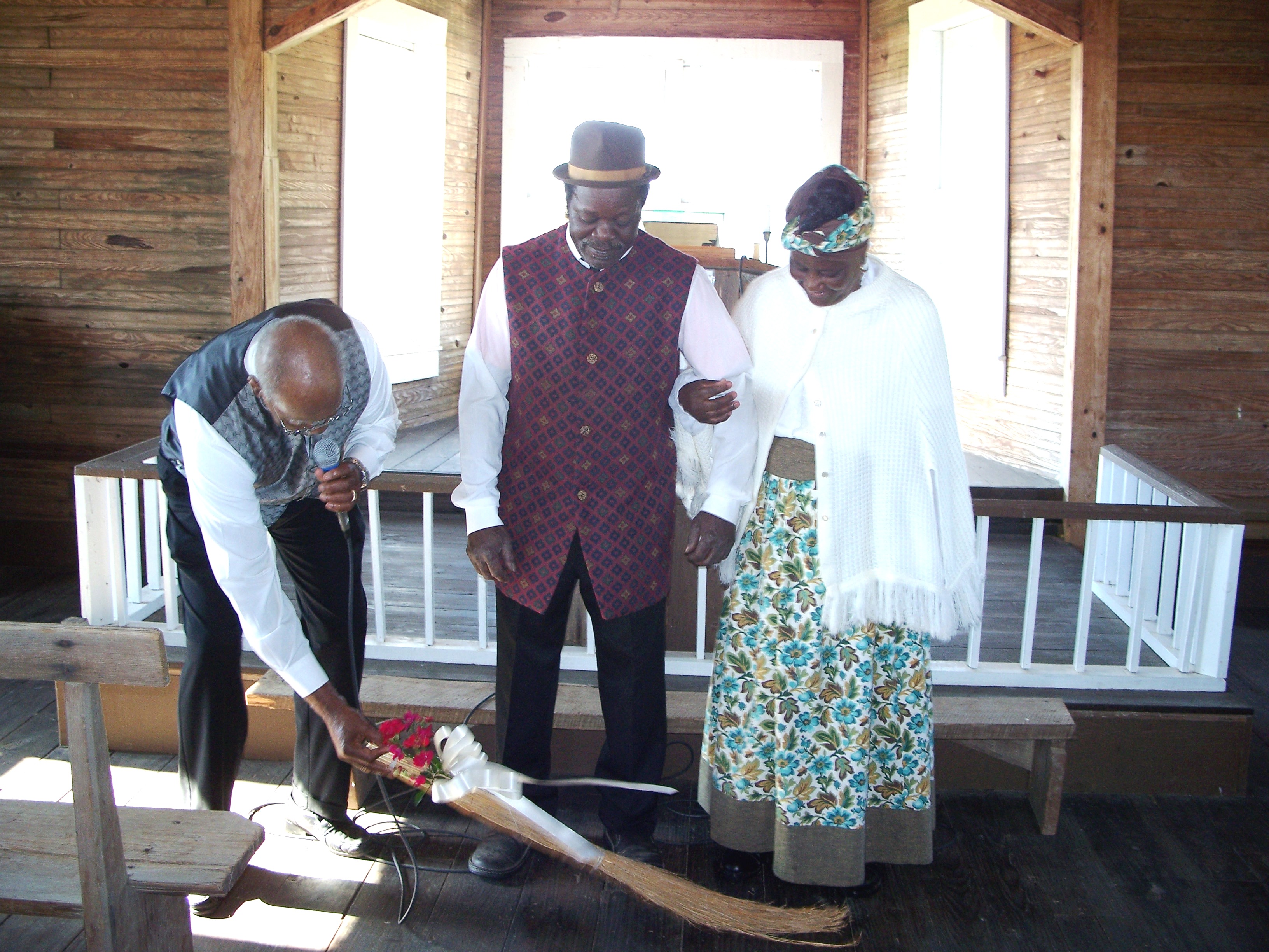 Married couple jumping over a broom.