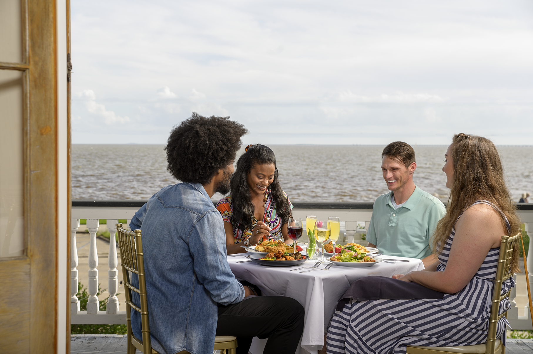 Four people enjoy food and wine by the water at The Lakehouse.