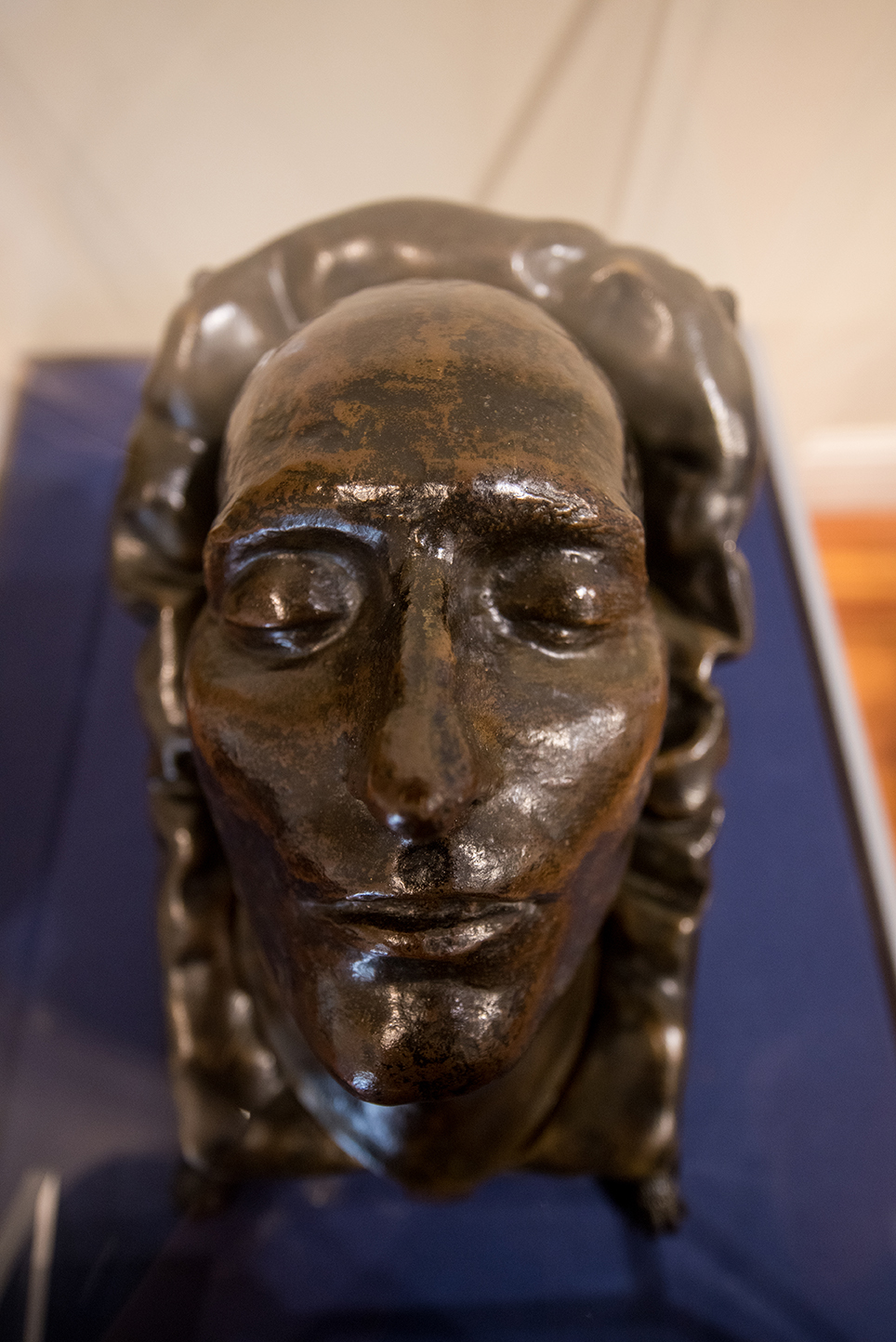A bronze death mask of a face in a museum exhibit