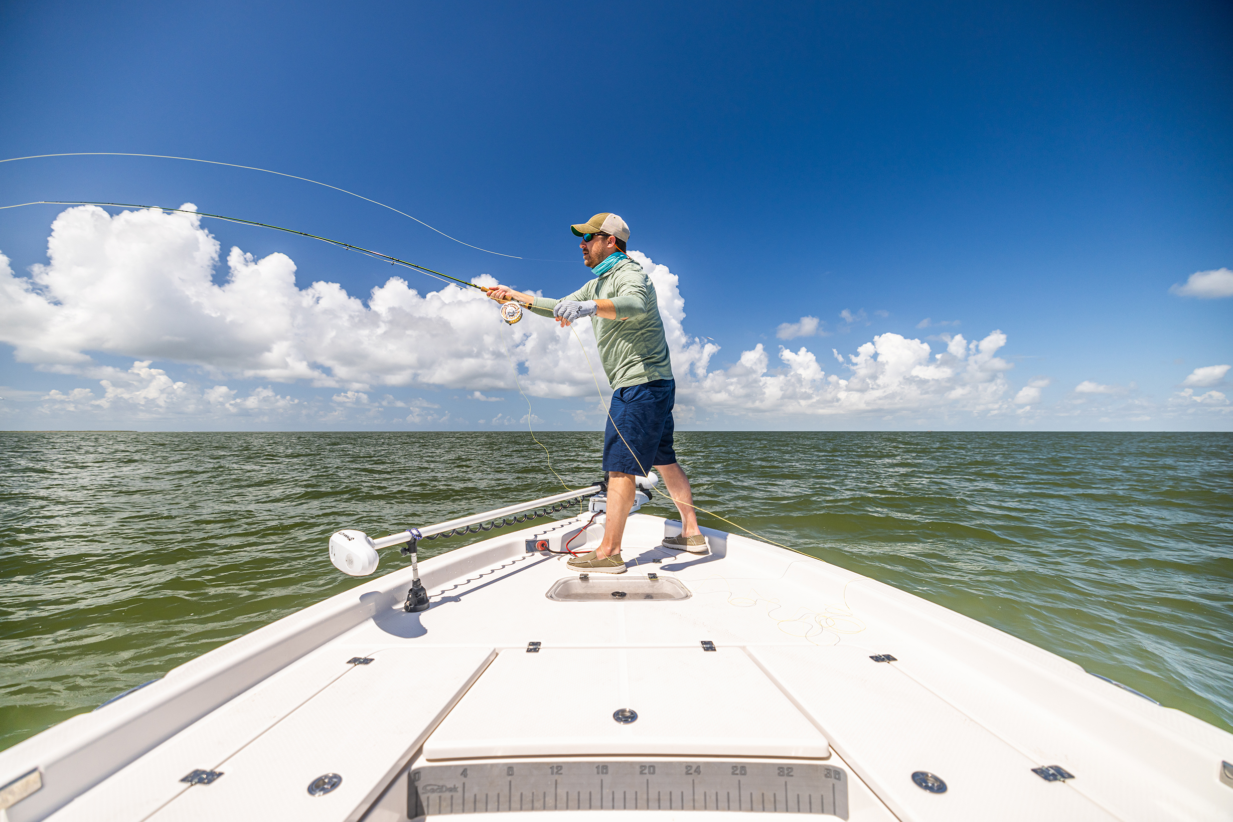 A man casts his line off the bow of a boat in the Gulf.