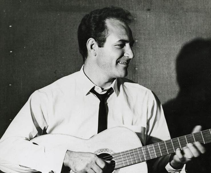 Fred Carter Jr. strums a guitar and smiles off to the viewer's right