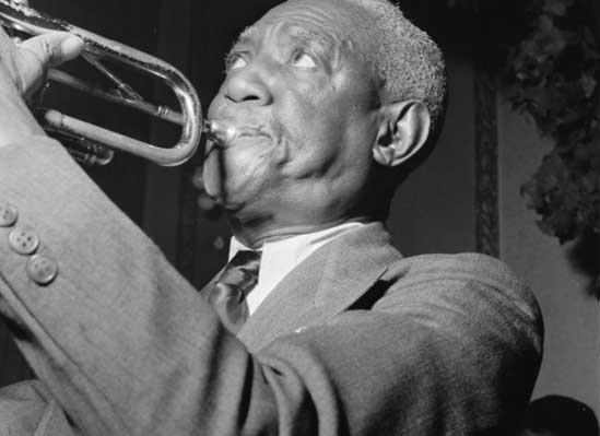 A side view of bunk blowing into his trumpet