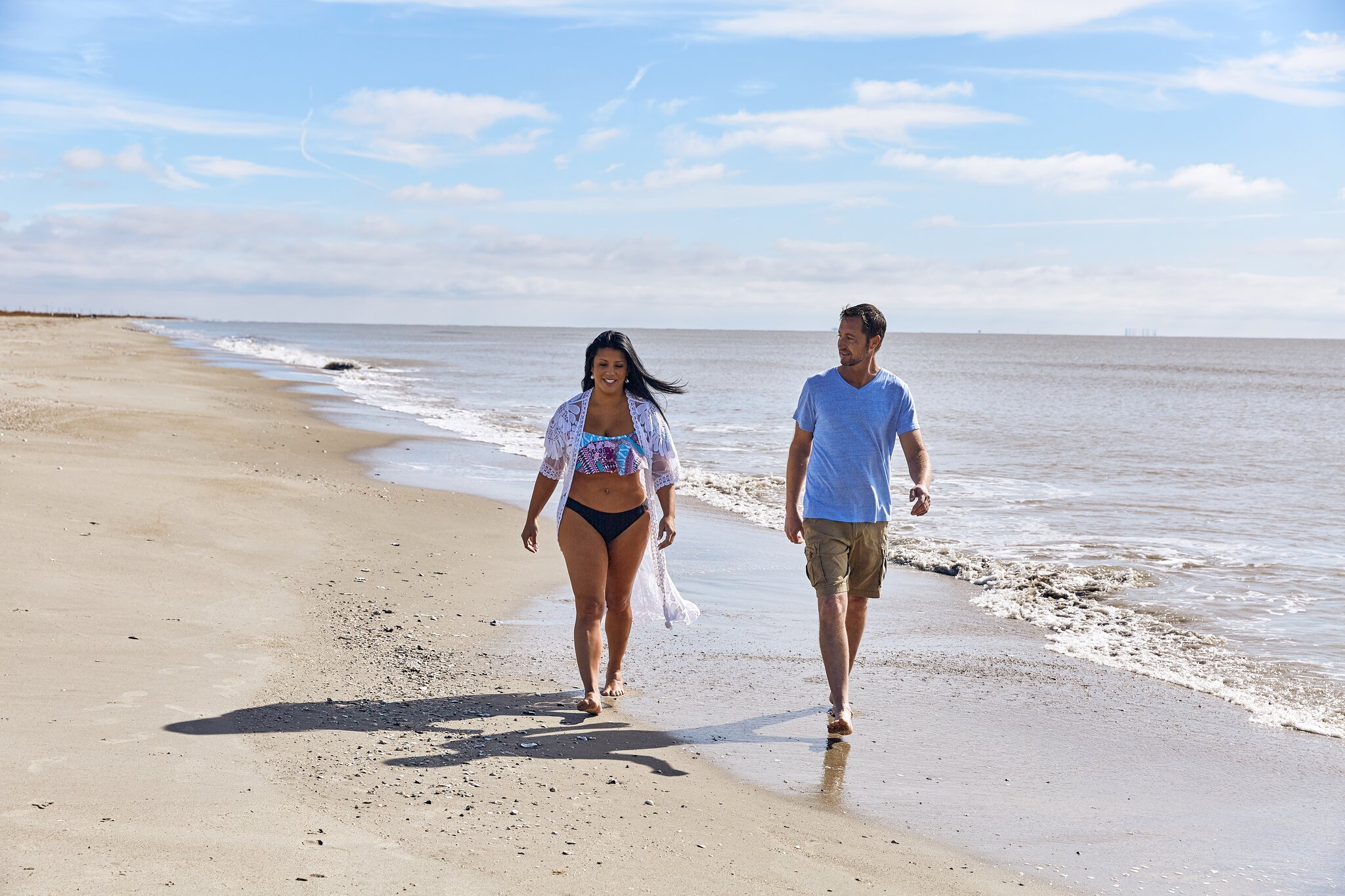 A man and woman walk along the shore of Holly Beach in Louisiana.