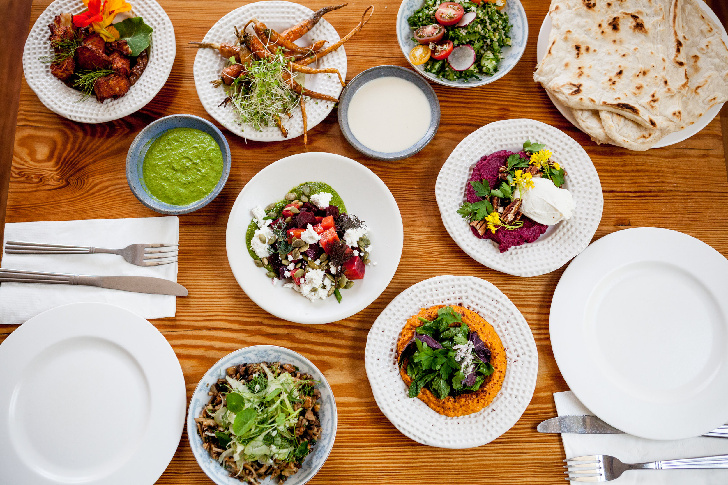 An array of Mediterranean dishes on a wood table at 1000 Figs in New Orleans