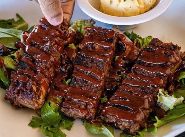 barbecue-sauce-covered jackfruit ribs sit on a bed of lettuce at Veganish Vibes in Baton Rouge