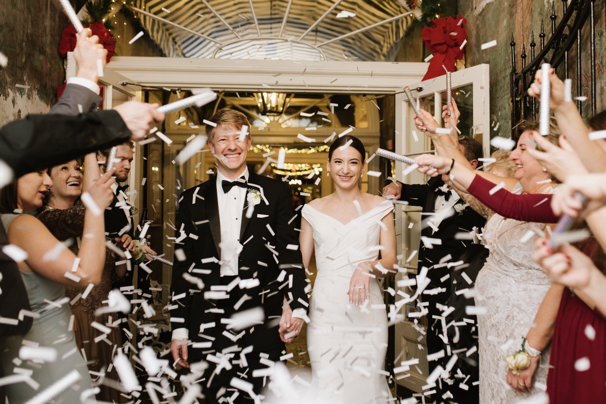 A couple exits their wedding beneath streams of confetti.