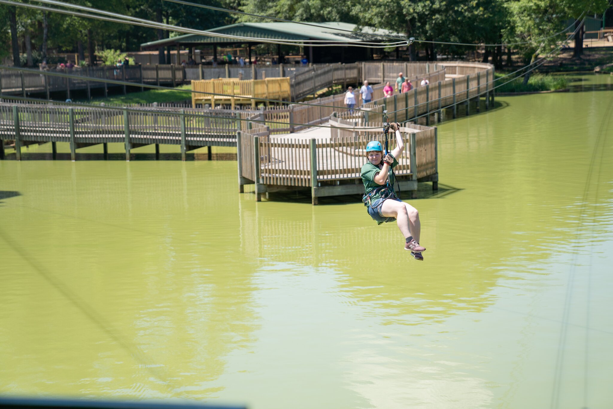 A child enjoys the zipline above light green water at Gators & Friends.