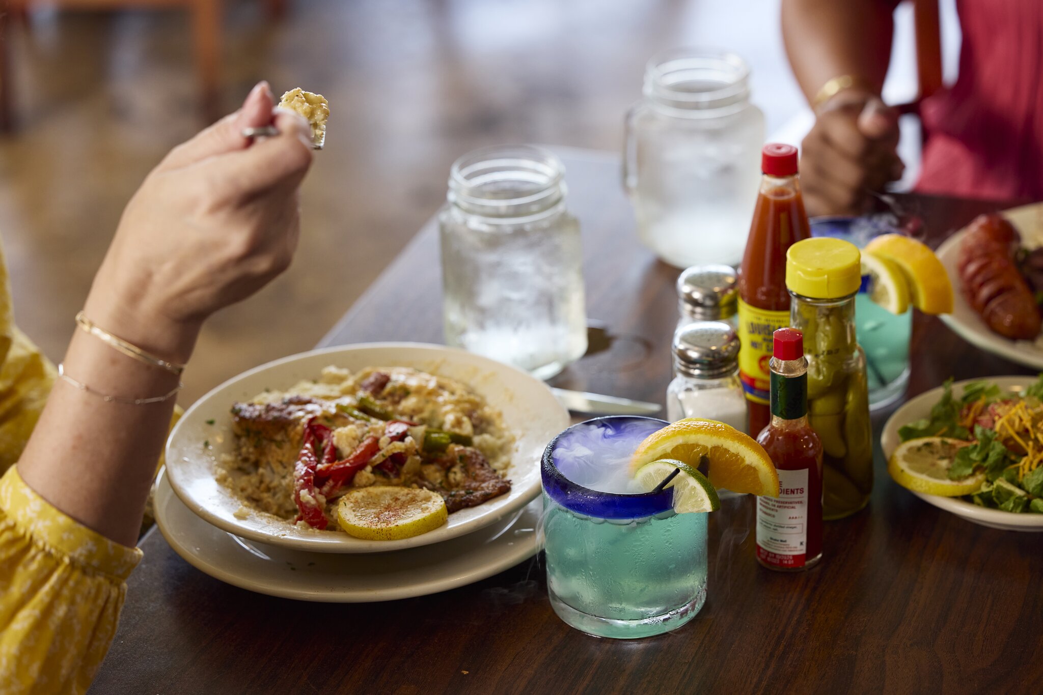 A table filled with Cajun and Creole dishes, hot sauces, spices and beverages at Orlandeaux’s Cafe.
