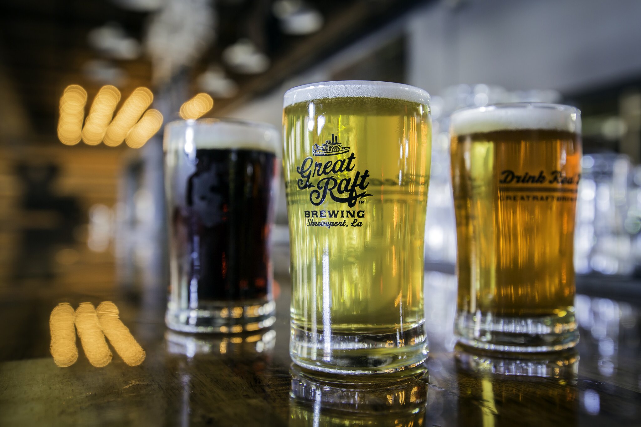 Three beers of varying shades atop a table at Great Raft Brewing.