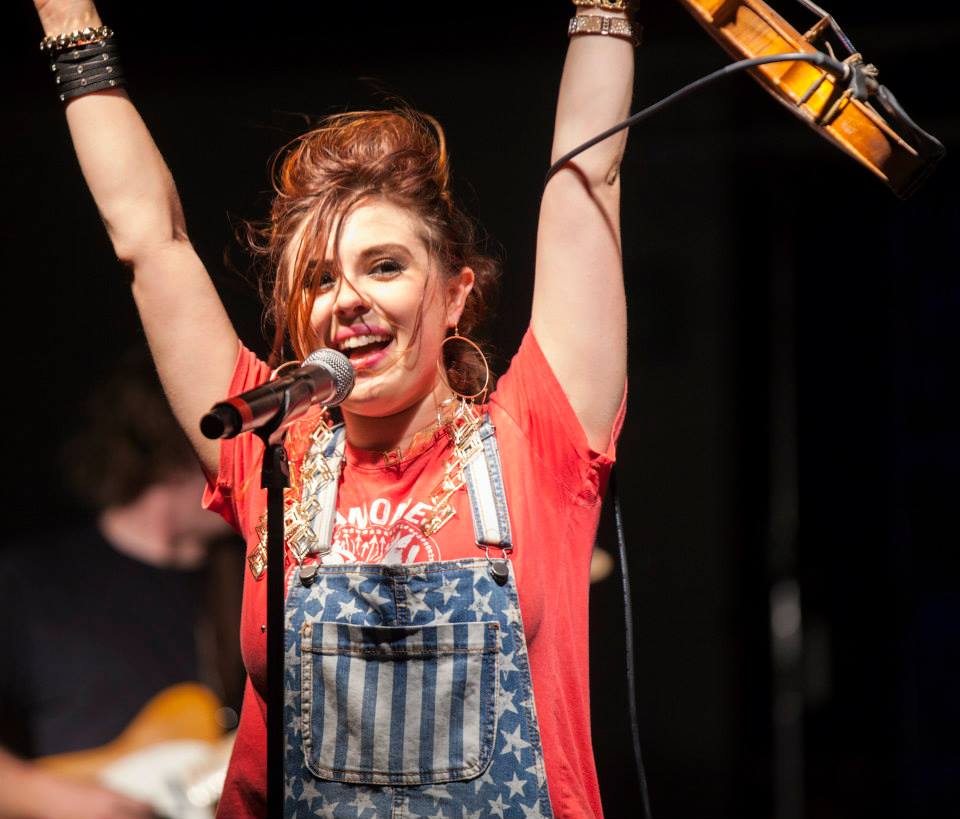 A female performer raises her arms above her head while performing at the Slidell Heritage Festival.