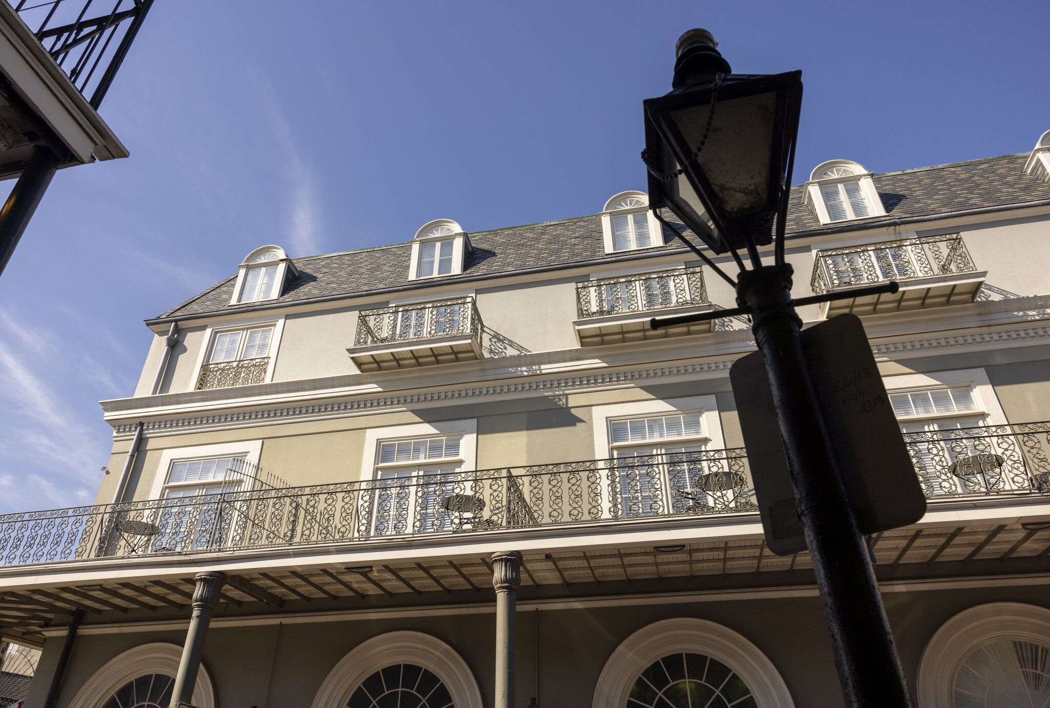 The exterior of the Bourbon Orleans, with wrought-iron balconies, softly lit by sunlight.