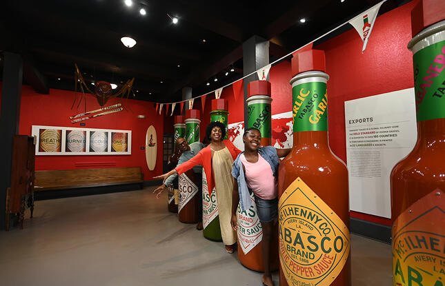 Two women pose with giant bottles of Louisiana-born TABASCO hot sauce.