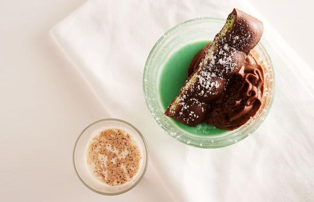 A mint-green cocktail flecked with chocolate rests on a white linen napkin.