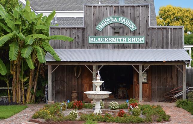 A wooden building reading "Gretna Green Blacksmith Shop" is set behind a white fountain