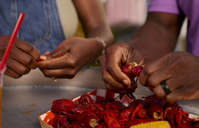 Two people peel crawfish together.