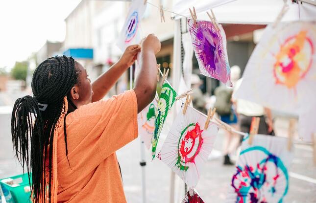 A festival-goer hangs their artwork from a line.