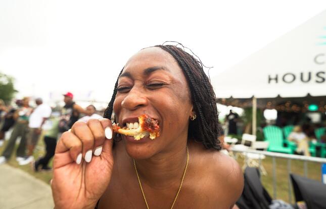 A person bites into a piece of fried chicken.