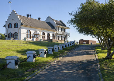Driveway leading up to a large white building on a hill with unique architectural features