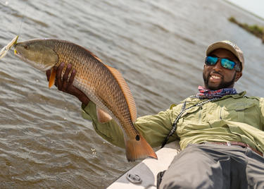 A man leaning over a boat and holding a large fish.