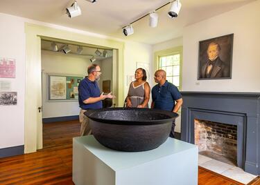 A tour guide provides information to a middle-aged couple at the E.D. White Historic Site in Louisiana.