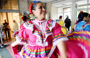 Women dressed in traditional Hispanic dancing dresses twirl.