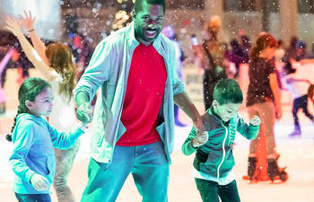 An adult helps two children ice skate.