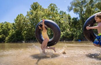 A girl runs along the water with an inner tube as she plays in Louisiana.