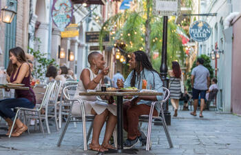 Guests eat exclusive dishes on a New Orleans patio, lit by glowing string lights, as part of COOLinary New Orleans.