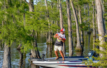 A man fishes from a boat in the bayou