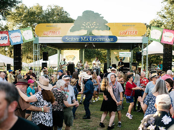 Dozens of people dance before a stage.