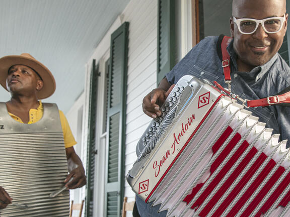 Two musicians play Zydeco music. They use a washboard and an accordion.