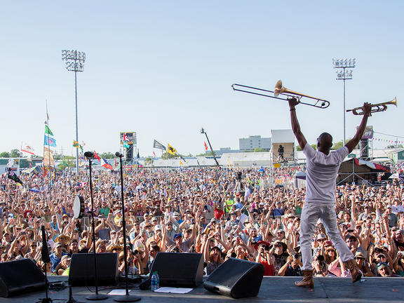 Trombone Shorty raises his instruments above his head while performing at Jazz Fest.