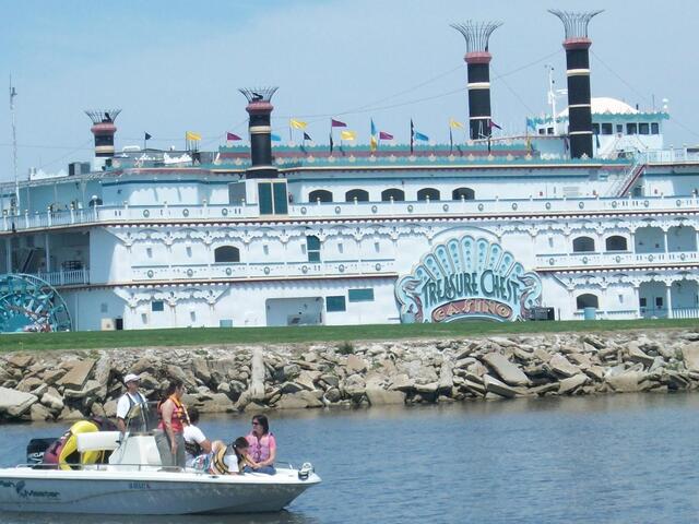 A family boating at Laketown in Kenner with the Treasure Chest Casino in the background.