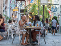 Guests eat exclusive dishes on a New Orleans patio, lit by glowing string lights, as part of COOLinary New Orleans.