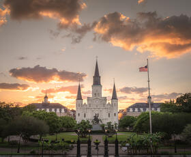 A white cathedral with spires in front of a sunset