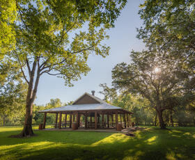 The group pavilion at St. Bernard State Park sits on a green, grassy hill, surrounded by trees.