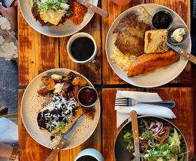 4 plates of breakfast food on a table with coffee and drinks