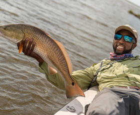 A man leaning over a boat and holding a large fish.