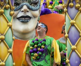 A Mardi Gras krewe rider smiles while on the float during the parade.