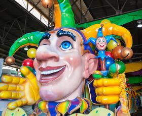 A decorated Mardi Gras float adorned with a giant purple, green and gold jester.