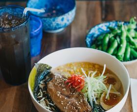 A bowl of pho topped with vegetables and broth.