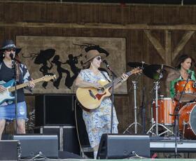 Singer playing guitar on stage during Jazz fest