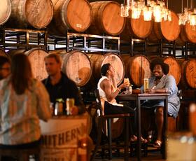 people at a brewery with barrels in the background