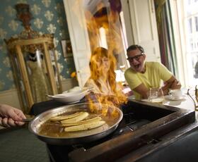 A table of diners look on excitedly as bananas foster are made table side at Brennan's.