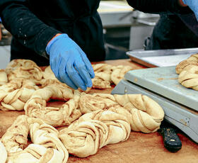 A baker twists king cake dough into ovals.