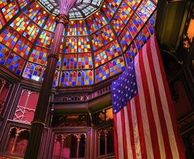 Vibrant stained glass dome with an American flag hanging inside a grand hall at Louisiana's Old State Capitol.