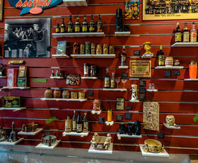 A red wall holds several shelves, each filled with bottles of all shapes, sizes and colors
