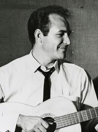 Fred Carter Jr. strums a guitar and smiles off to the viewer's right