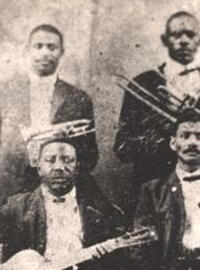 Four men stand with a bass, trumpet, trombone and clarinet, while two sit with guitars in a sepia-toned setting