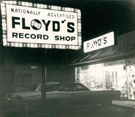 A black and white image of Floyd's lit-up sign and entrance